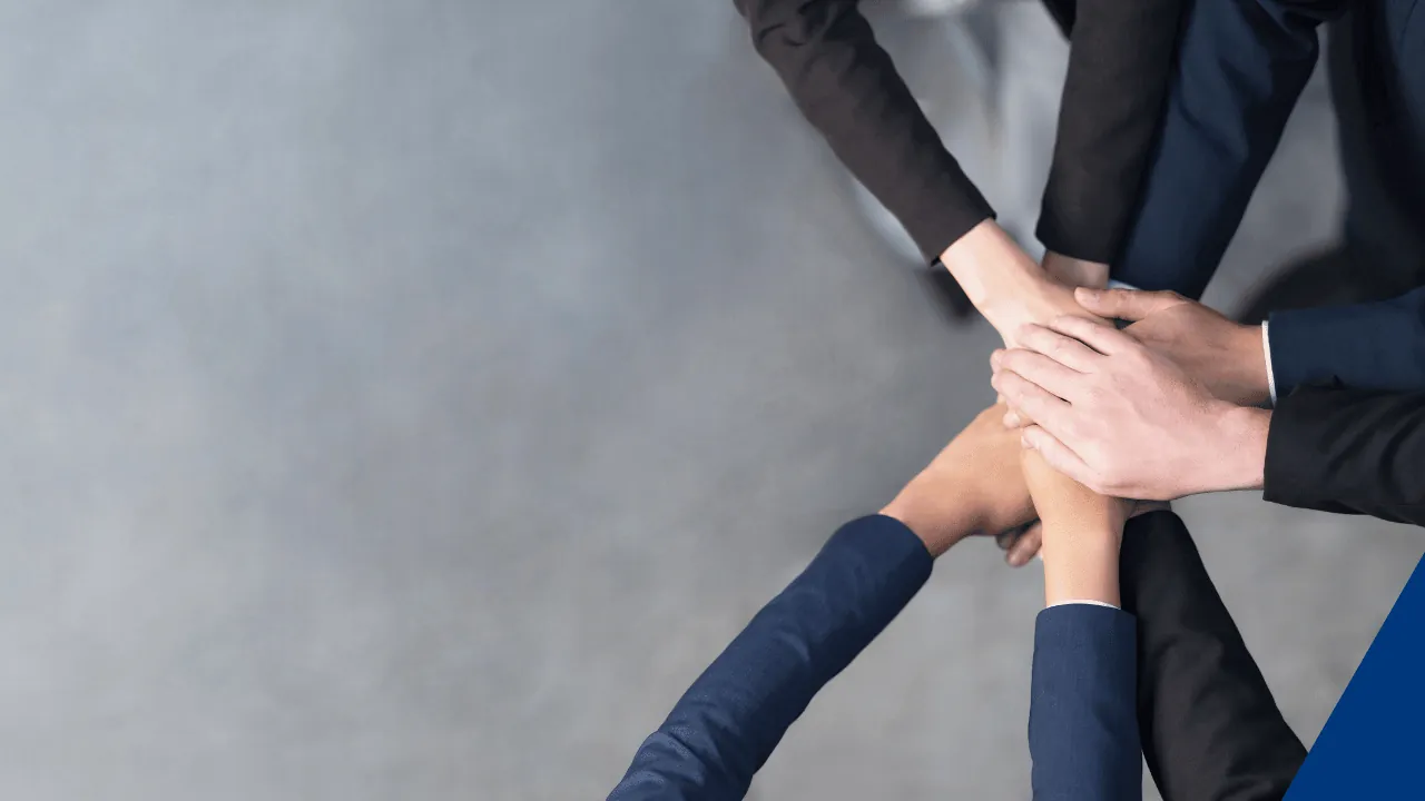Teamwork-Hände in der Mitte eines Workshops, die auf häufige Workshop-Fehler hinweisen.