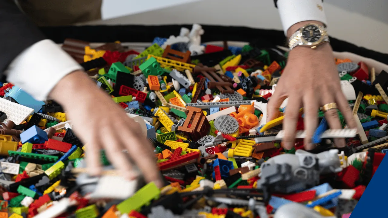 Hände in einem Berg bunter LEGO-Steine, die häufig bei Workshops verwendet werden.