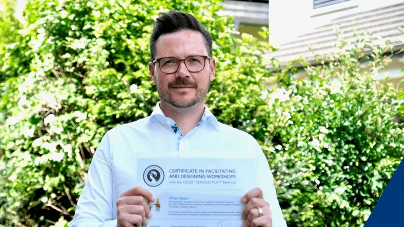 Oliver Gabor hält das Diplom als LEGO Serious Play Facilitator hoch