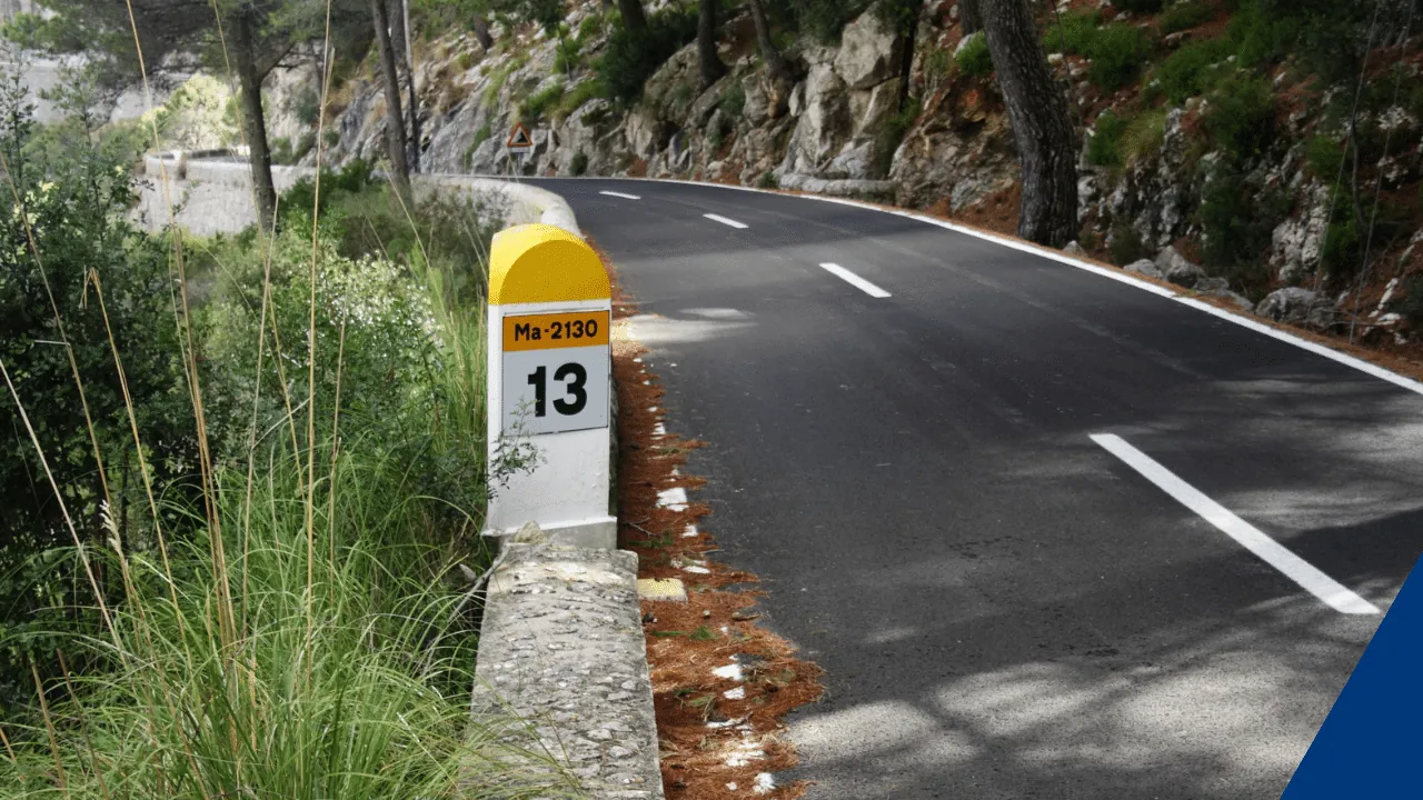 Strasse zwischen Felswand und Abhang mit Meilenstein 13